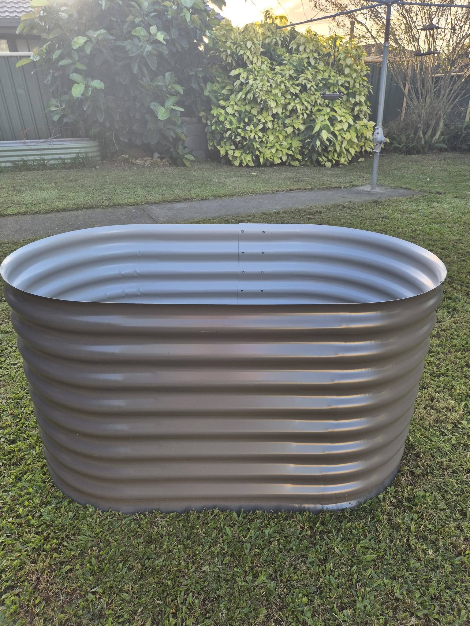 Handmade corrugated aquaplate steel raised garden bed sitting on green lawn